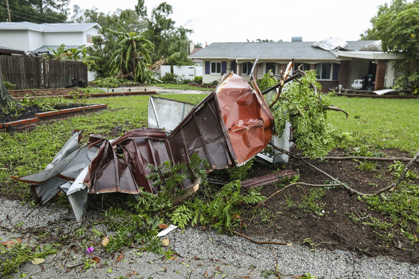 Storm damage and downed limbs beside a home